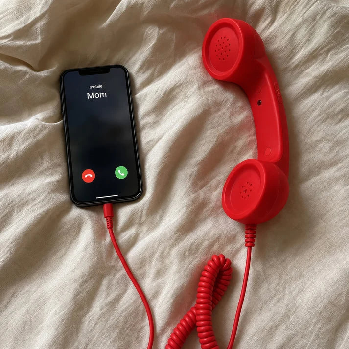 Red handset connected to smartphone on bedding