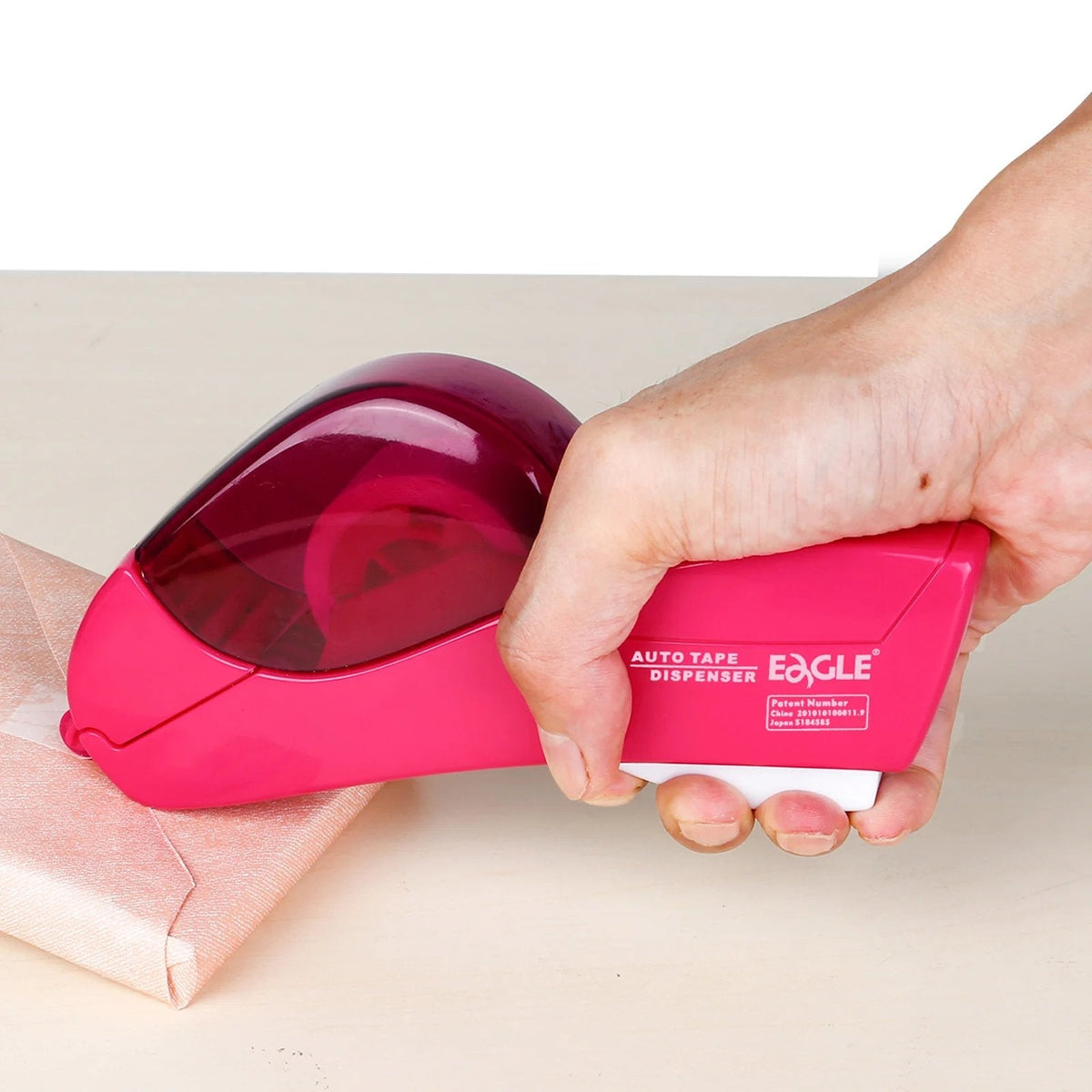 One hand using tape dispenser on gift wrap