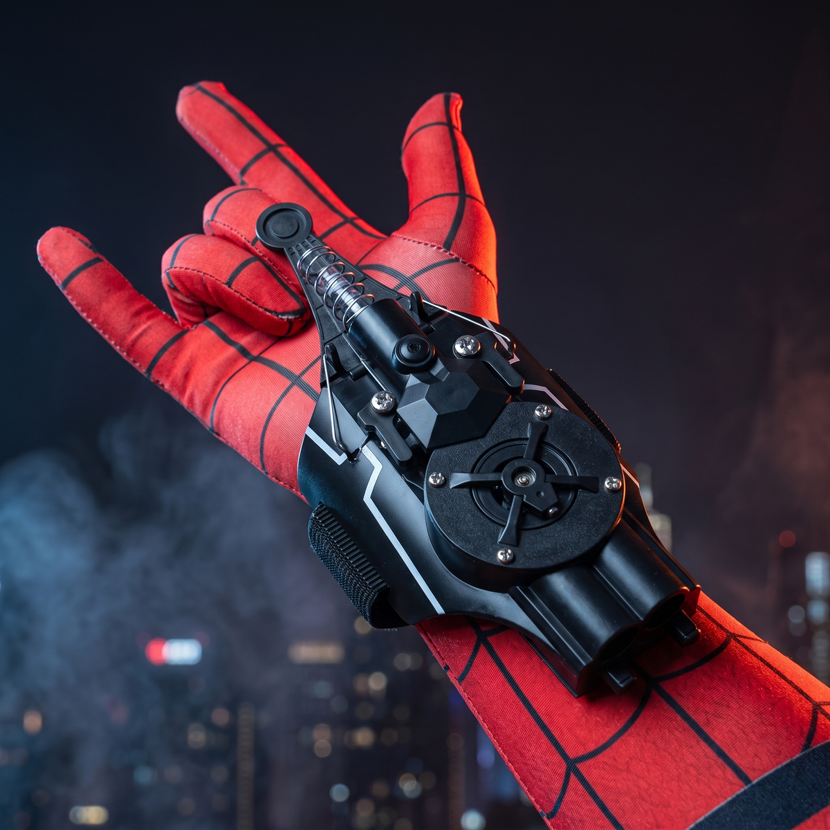 Black retractable wrist launcher shown over a red patterned costume glove against a dramatic city background